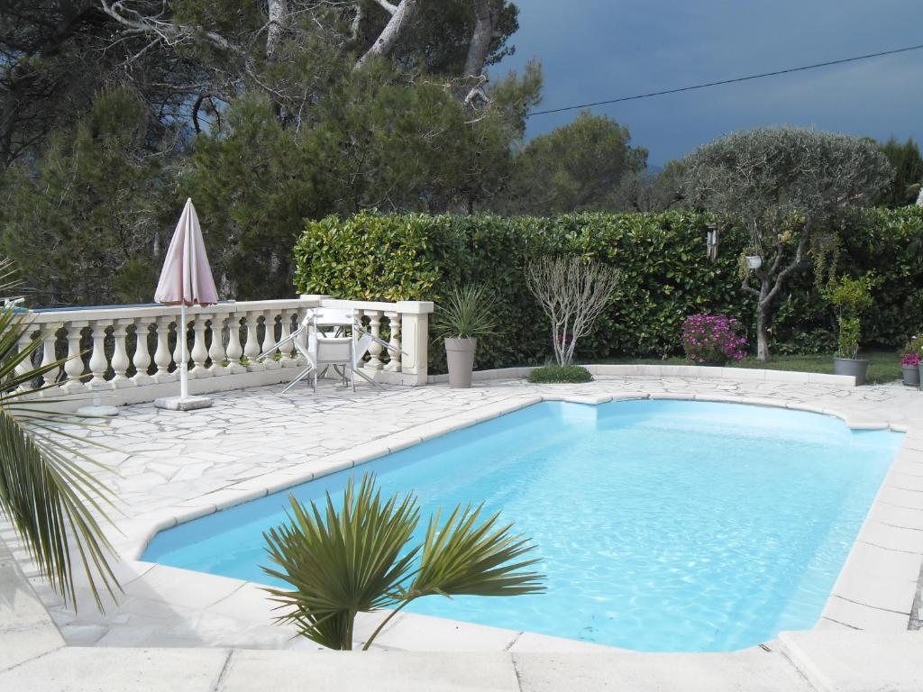 a swimming pool with a patio and an umbrella at Charmante Villa à 15 min de Nice avec piscine in Blausasc