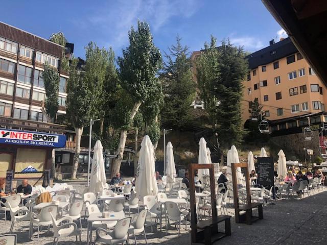grupa stołów i krzeseł z białymi parasolami w obiekcie Apartamento Plaza Pradollano 2 w mieście Sierra Nevada