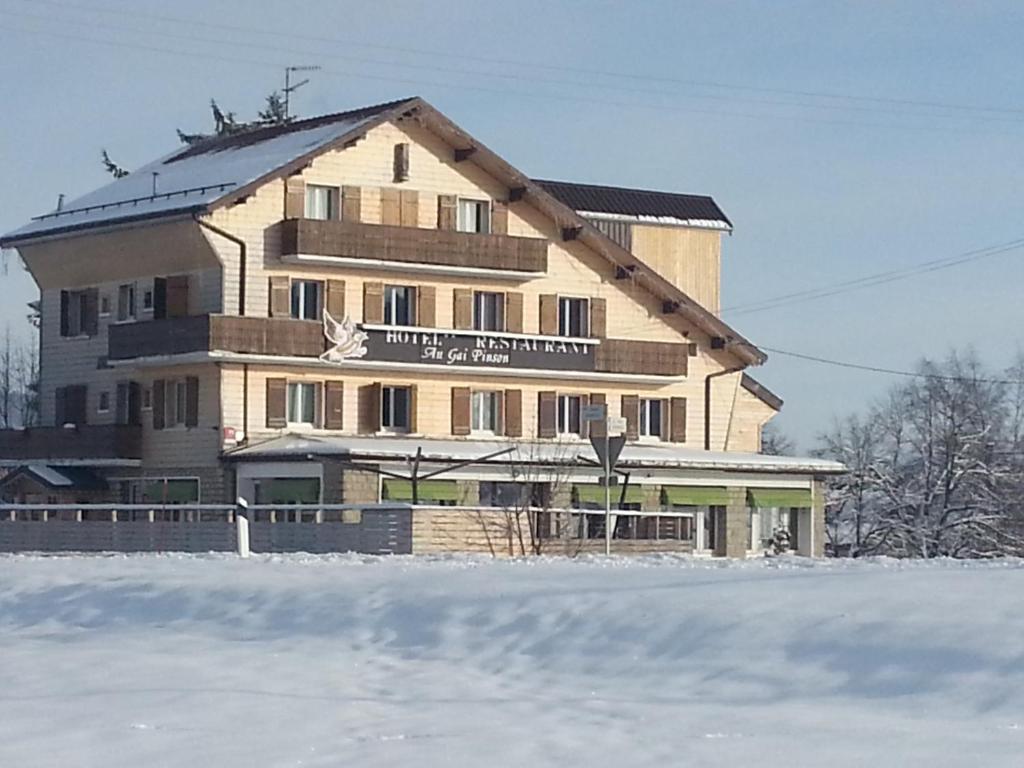 duży budynek w środku pokrytego śniegiem pola w obiekcie Hotel Restaurant LE YETI ancien Gai pinson w mieście Les Rousses