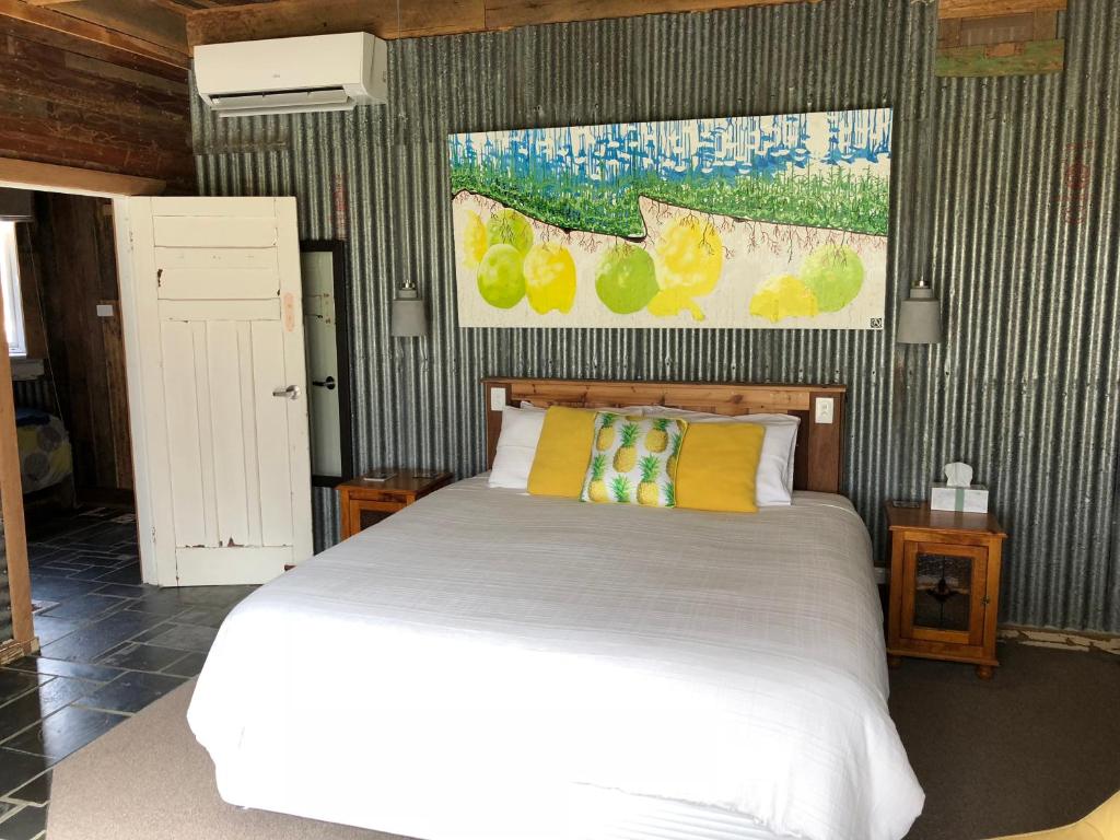 a bedroom with a white bed and a painting on the wall at Bed in a Shed Vineyard Stay in Watervale