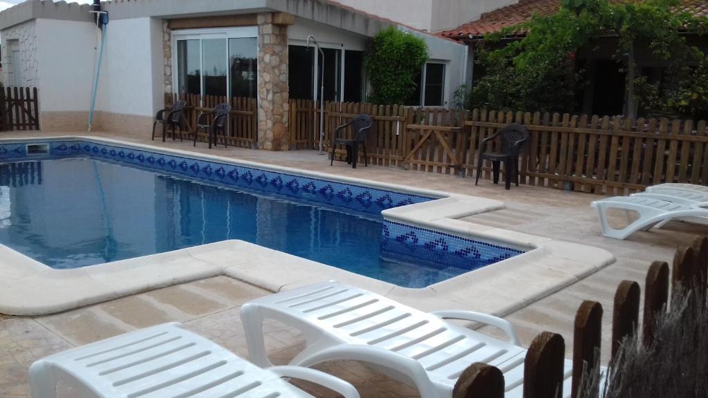 a swimming pool with lounge chairs next to a house at Les Casetes de Camarles in Camarles