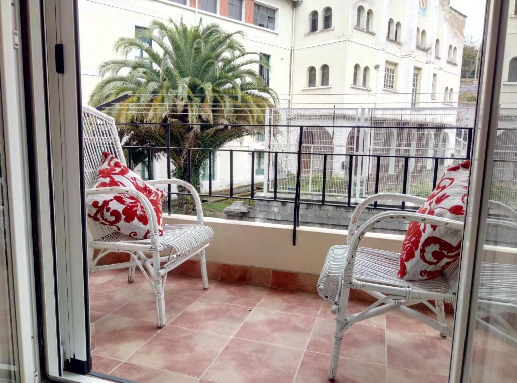 two chairs sitting on a balcony with a window at Apartamento centrico en Lekeitio, playa y puerto in Lekeitio
