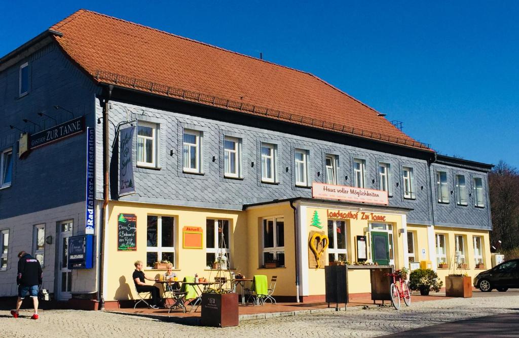 um edifício com pessoas sentadas em mesas fora dele em Landgasthof Zur Tanne em Waltershausen