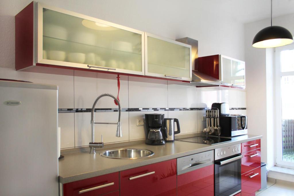 a kitchen with red cabinets and a sink at Ferienwohnung City in Erfurt