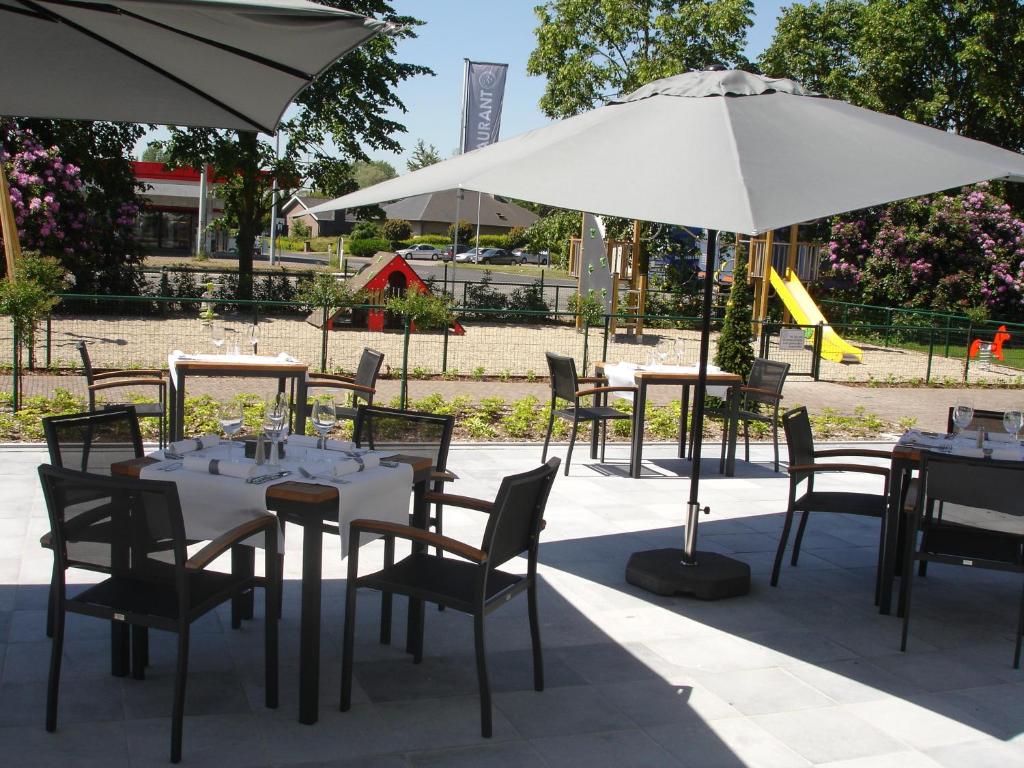 a group of tables and chairs with white umbrellas at Biznis Hotel in Lokeren
