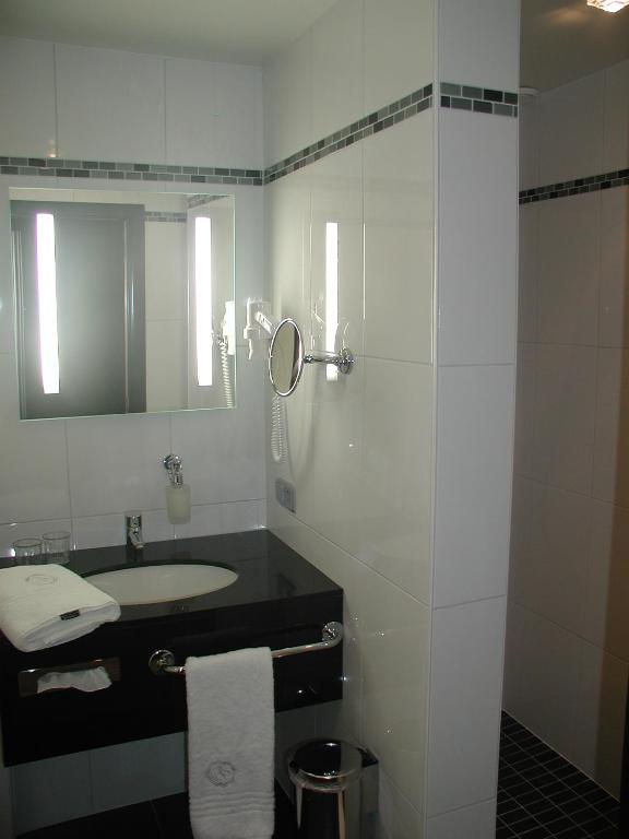 a white bathroom with a sink and a mirror at Biznis Hotel in Lokeren