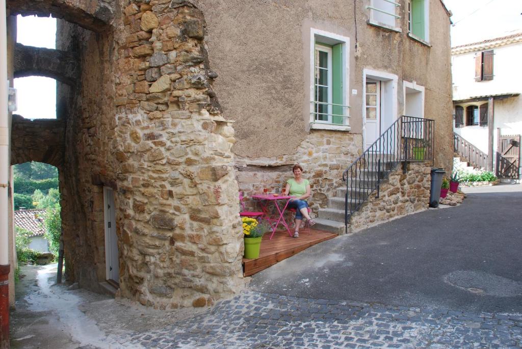 Neffies Languedoc Frankrig في Néffiès: امرأة تجلس على طاولة خارج المبنى