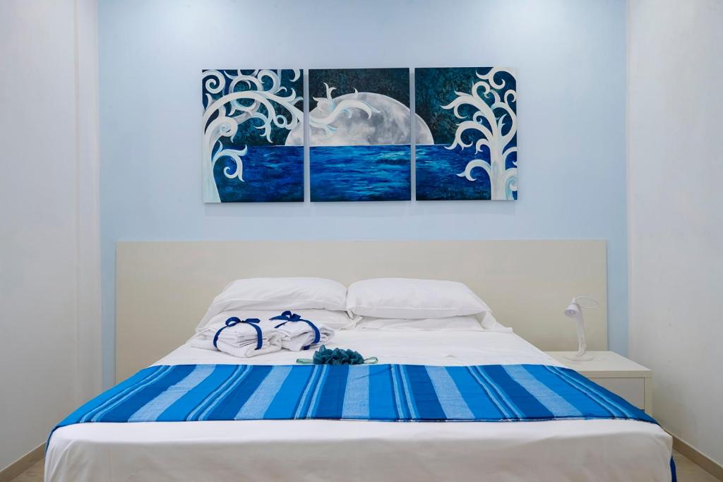 トラーパニにあるTrapani a mareの白いベッド(壁に青と白の絵画2点)