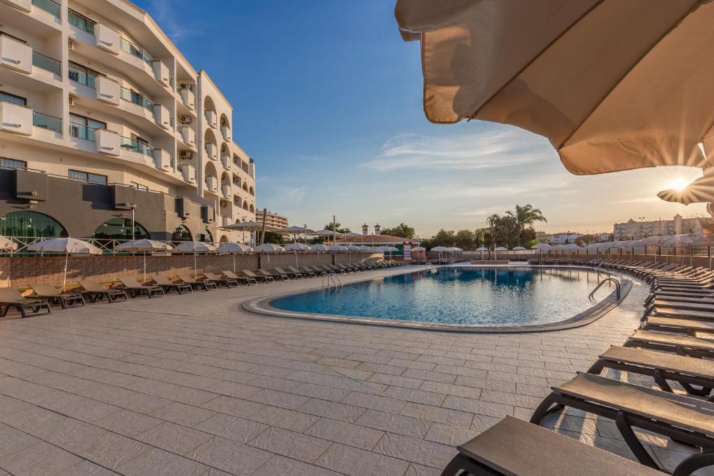 einen Pool in einem Resort mit Stühlen und einem Gebäude in der Unterkunft Luna Solaqua in Albufeira