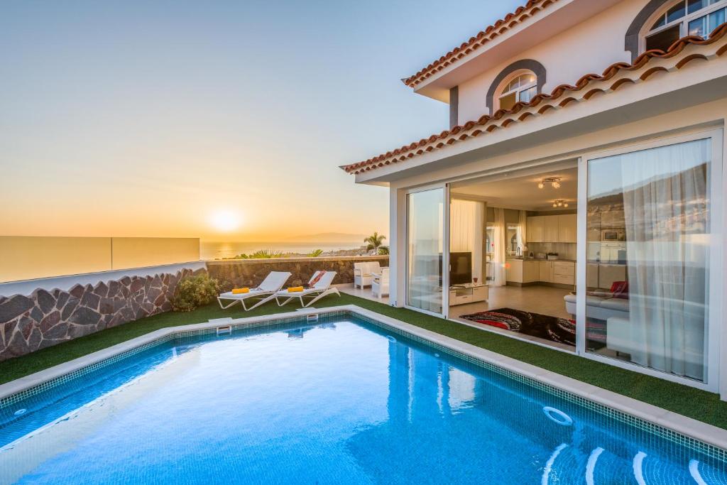 a swimming pool in front of a house at LUXURY WHITE VILLA with sea view, heated pool in Adeje