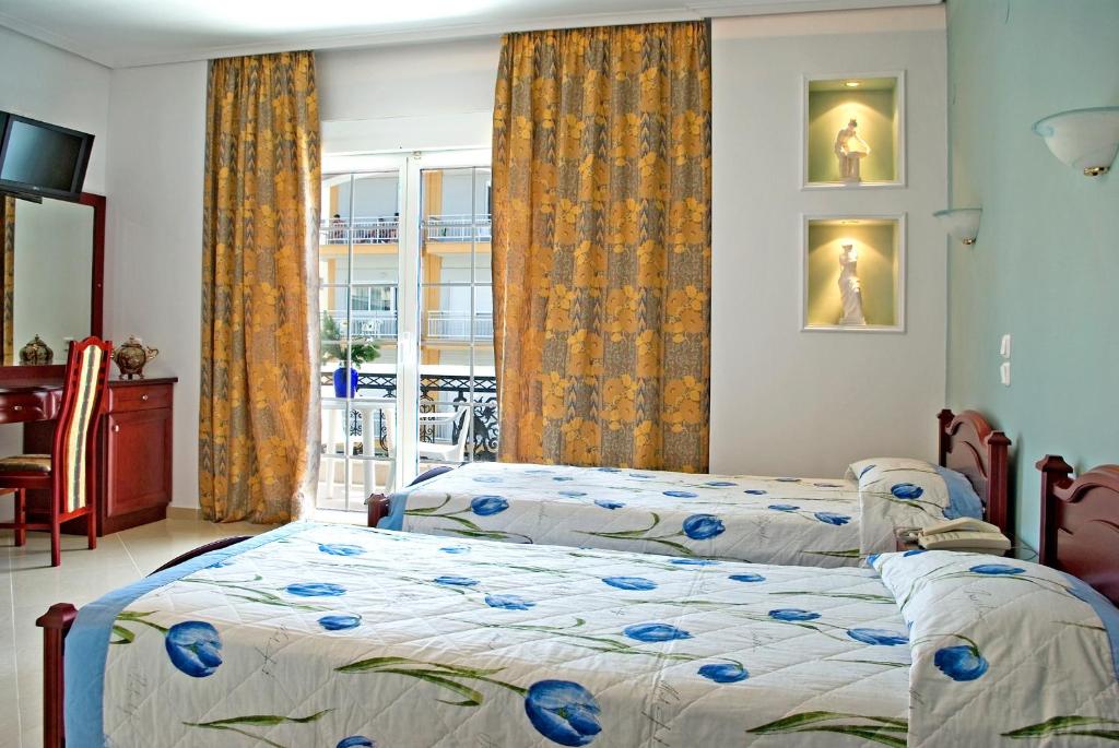 1 dormitorio con 2 camas y ventana en Hotel Chronis, en Paralia Katerinis