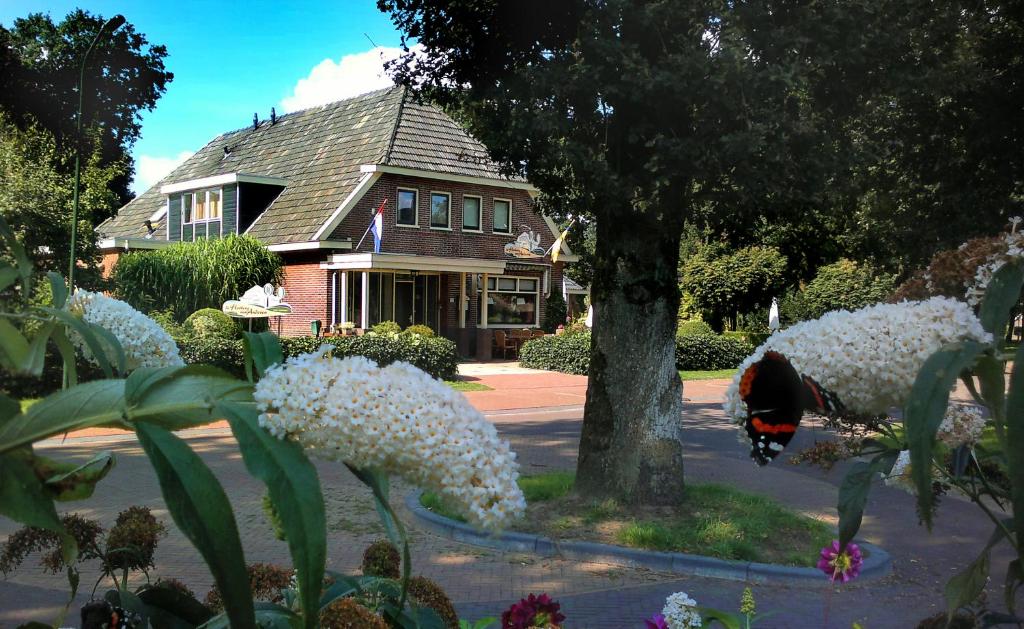 una casa con flores blancas delante de un árbol en De Herberg van Anderen en Anderen