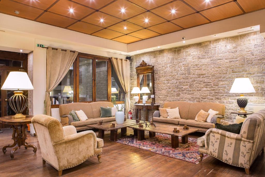 a living room with furniture and a brick wall at Country Club Hotel & Suites in Mikro Chorio