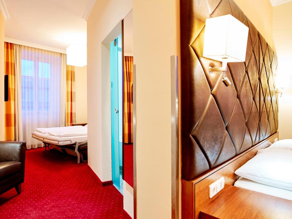ザルツブルクにあるヴィラ チェコニ バイ ダス グリューネ ホテル ツア ポスト 100% ビオの赤いカーペットフロアの客室で、ベッド2台が備わります。