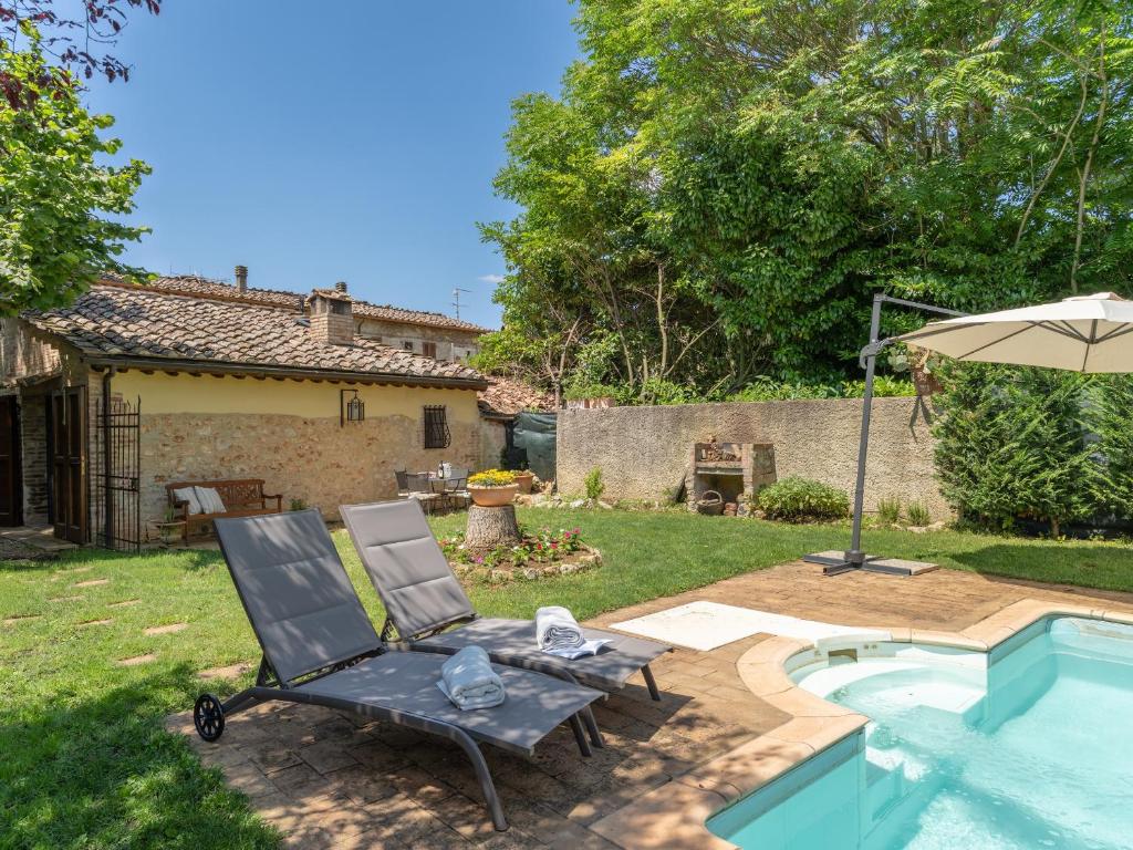 a patio with a chair and an umbrella next to a pool at Casina di Teo by VacaVilla in Monteriggioni