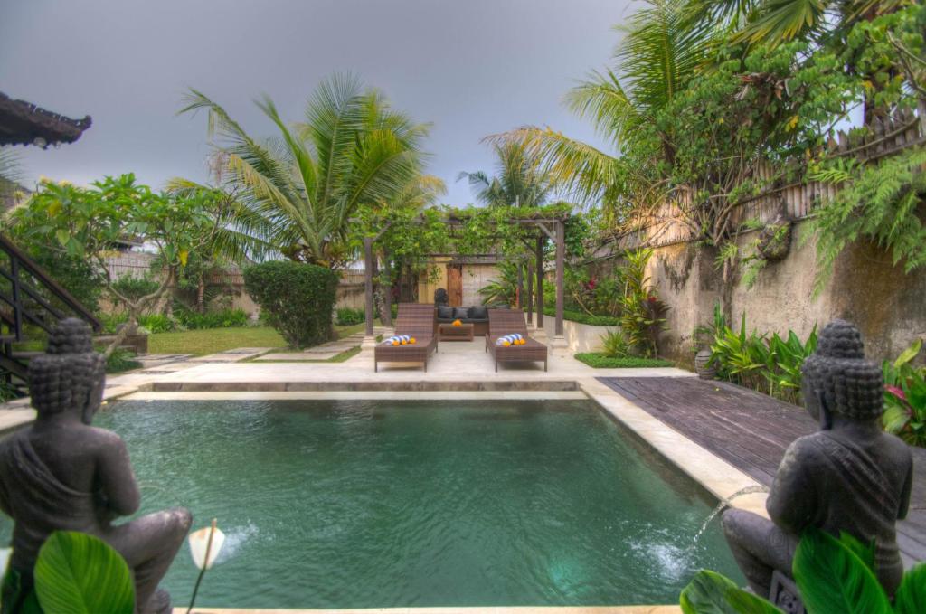 a swimming pool with two statues in front of a house at Villa Kami Ubud in Ubud