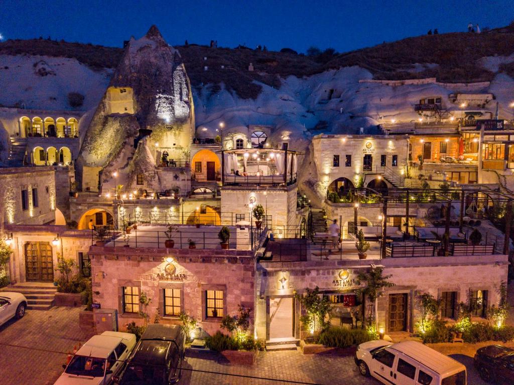 um edifício com carros estacionados num parque de estacionamento à noite em Artemis Cave Suites & Spa- Adults Only em Goreme