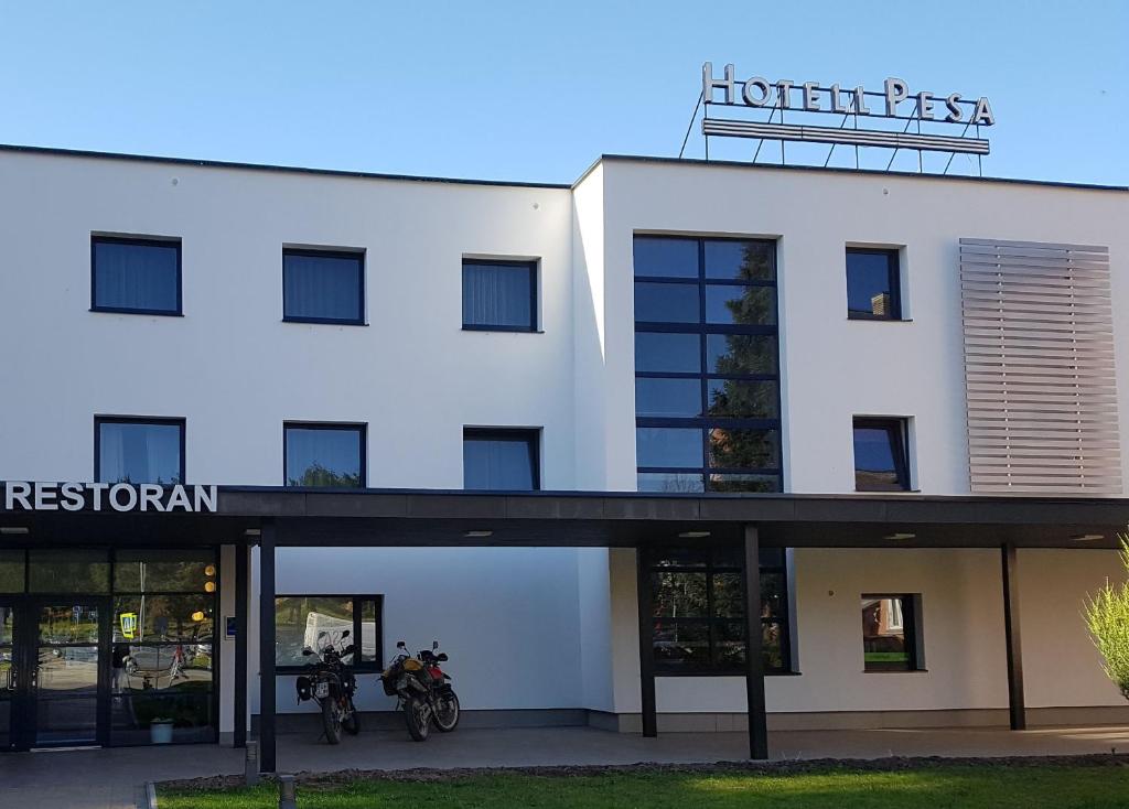 un edificio blanco con dos personas en bicicleta delante de él en Pesa Hotel en Põlva