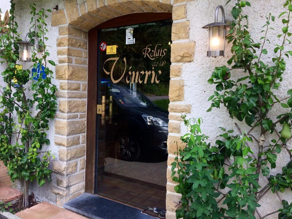 a door to a restaurant with a car in the window at Hotel La Venerie in Virton