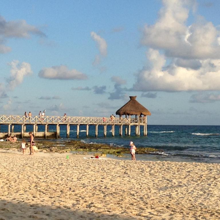a group of people on the beach near a pier at Suites at Mayan Palace Vidanta Resort Riviera Maya in Playa del Carmen