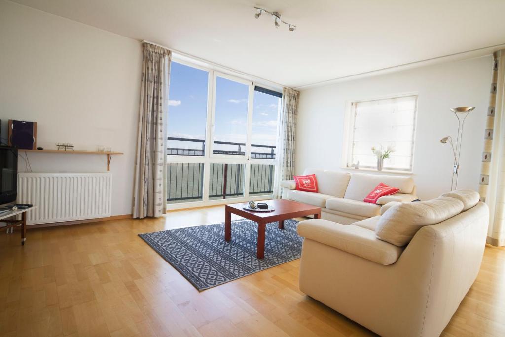 Hello Zeeland - Appartement Port Scaldis 13-111 في بريسكين: غرفة معيشة مع أريكة وطاولة