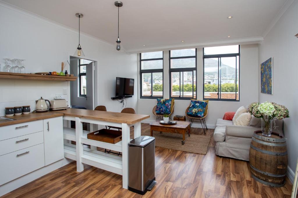 a kitchen and living room with a table and a couch at Trendy Cape Town CBD Apartment in Cape Town