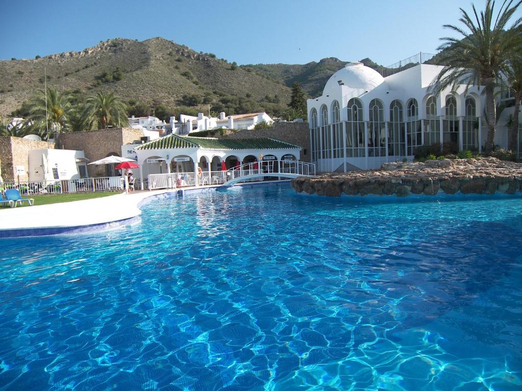 a swimming pool with blue water in front of a building at Nerja Villas-Capistrano in Nerja