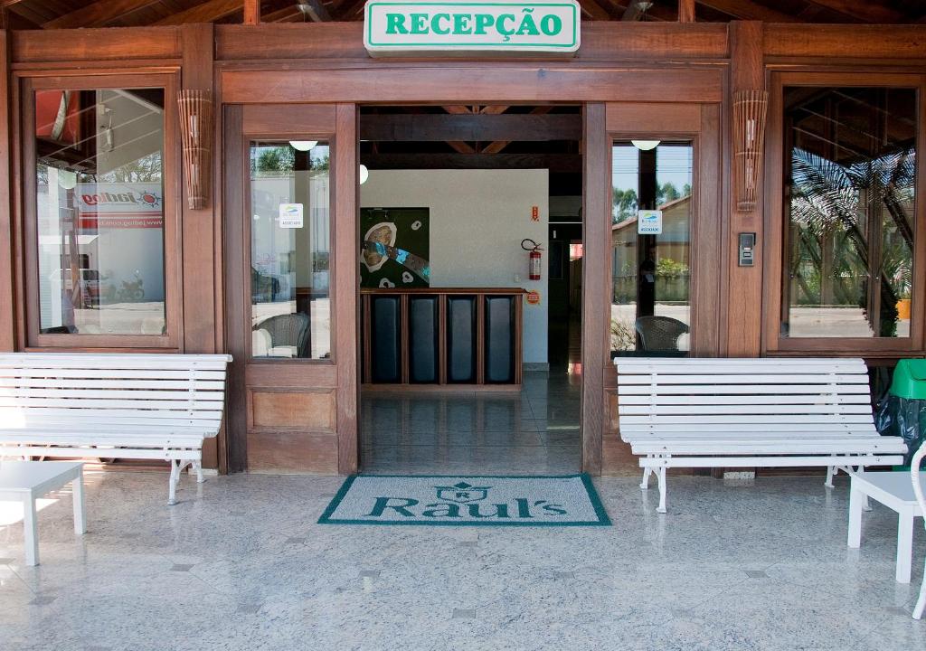 two white benches sitting outside of a building at Hotel Raul's in Gaspar