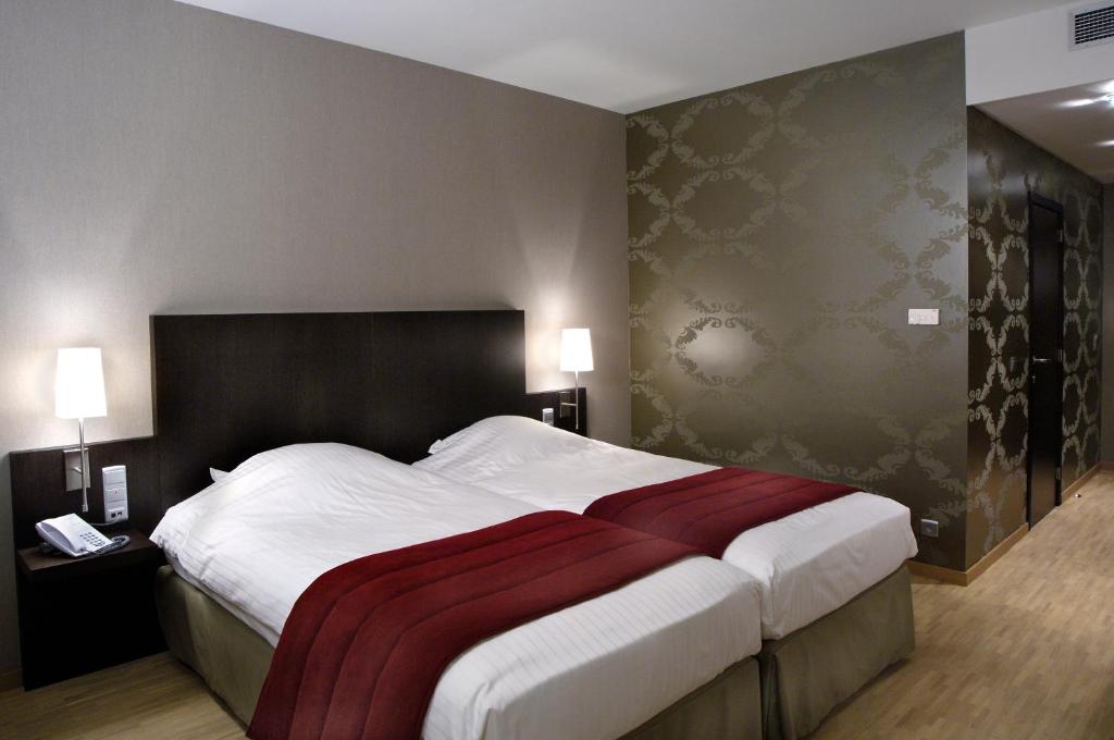 a bedroom with a large bed with a red blanket on it at Biznis Hotel in Lokeren