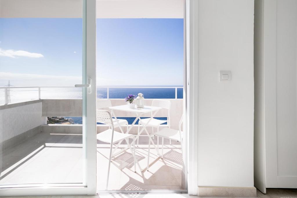 a balcony with a table and chairs and a view of the ocean at Breathtaking 180 degrees Views in Tabaiba Alta in Santa Cruz de Tenerife