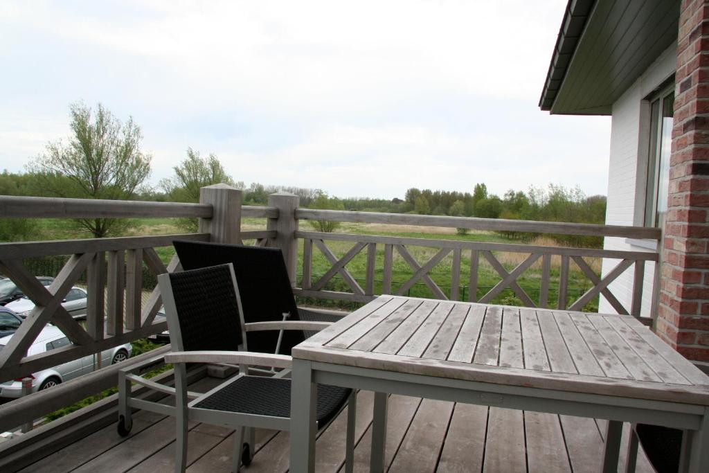 a wooden table and two chairs on a deck at Biznis Hotel in Lokeren