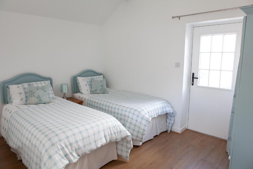 a bedroom with two beds and a door at Elm Cottage Touring Park in Whitegate