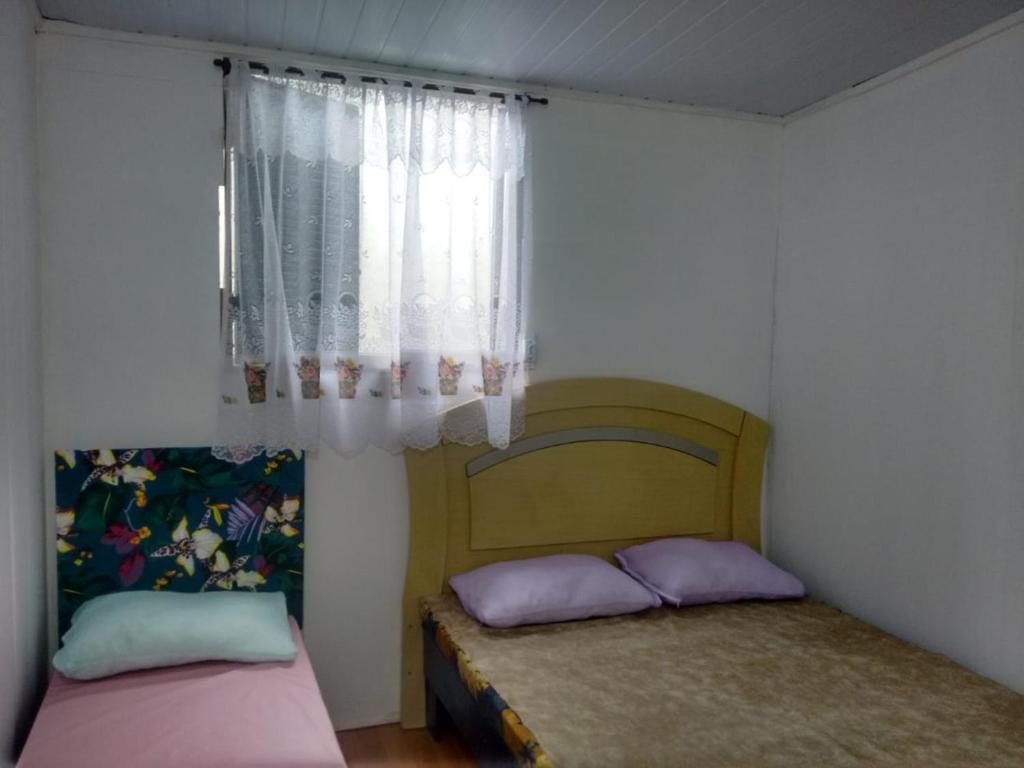 two beds in a small room with a window at Apartamento Da Praça in Arraial do Cabo