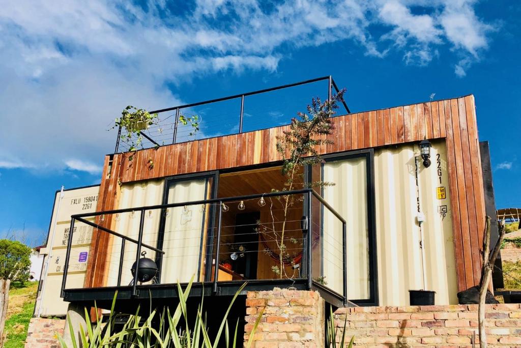 uma casa com portas de vidro em cima de uma parede de tijolos em EnCubo Glamping Guatavita em Guatavita