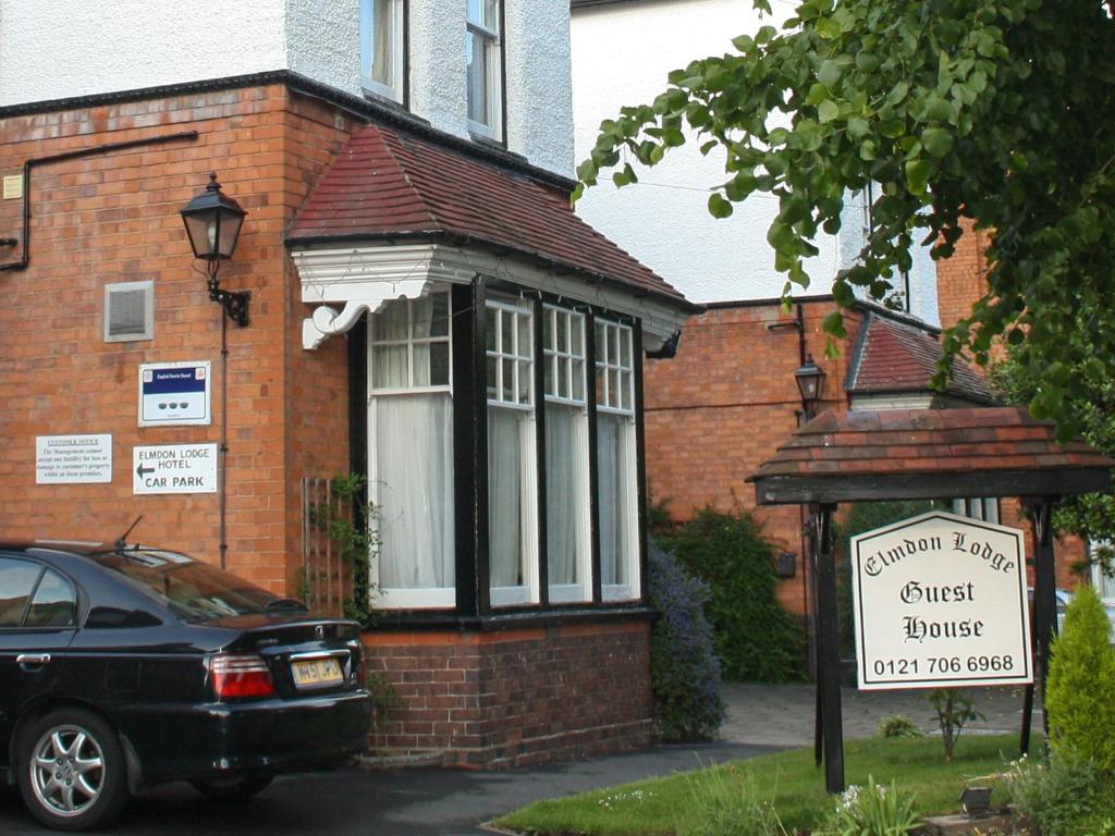 a small brick house with a sign in front of it at Elmdon Lodge in Birmingham