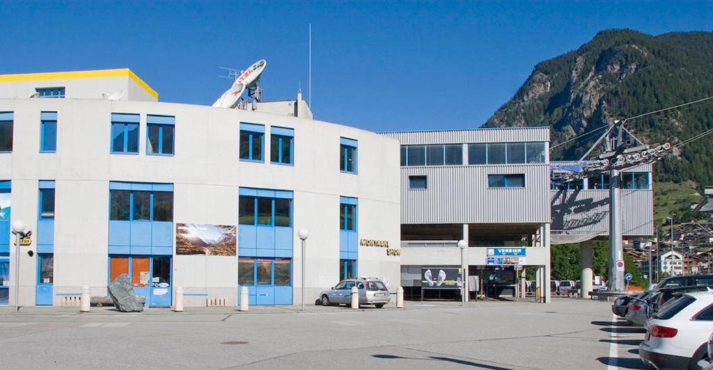 ein weißes Gebäude mit Autos auf einem Parkplatz in der Unterkunft Mont-Fort Swiss Lodge in Le Châble