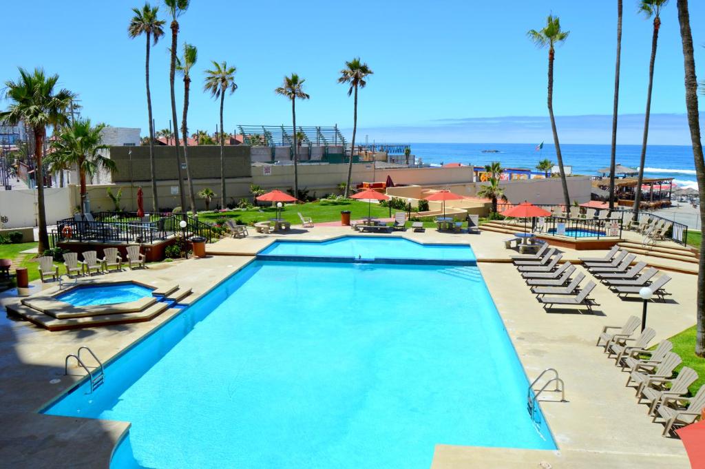 a pool at a resort with palm trees and the ocean at Rosarito Inn in Rosarito