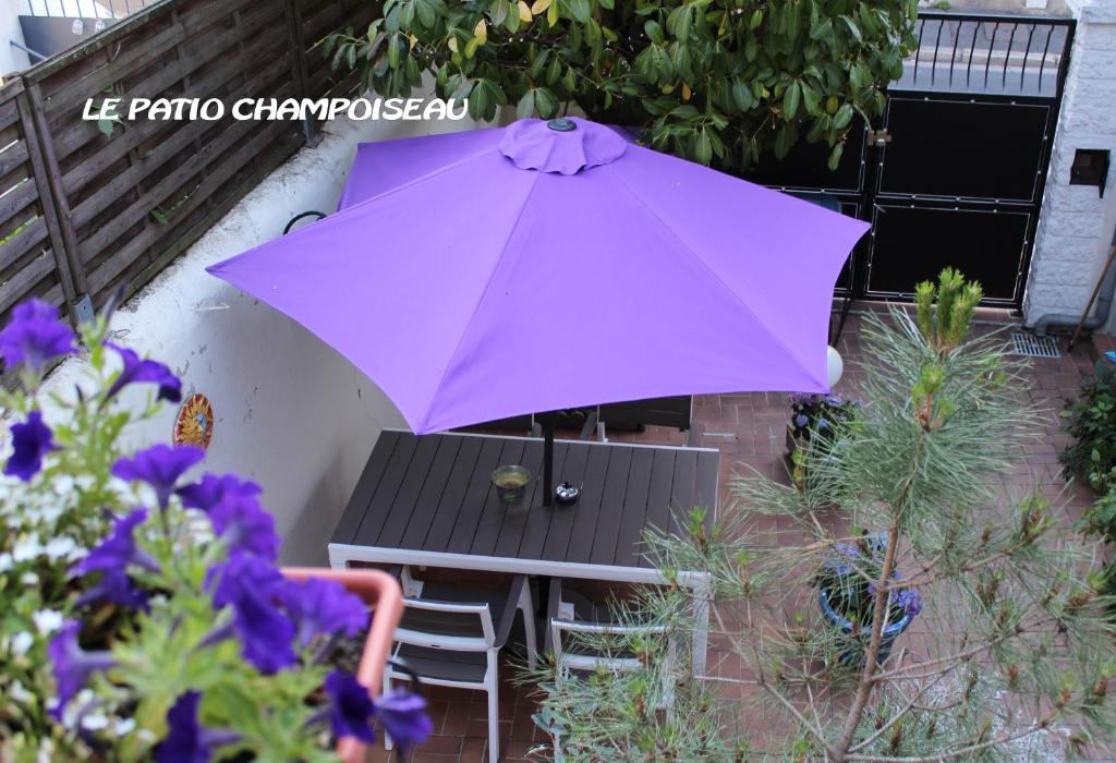 un paraguas púrpura sobre una mesa y un banco en Champoiseau en Tours