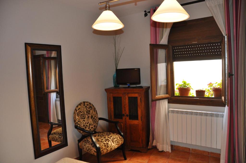 チンチョンにあるCasa Rural El Abuelo Quikoの椅子と鏡が備わる窓のある客室です。