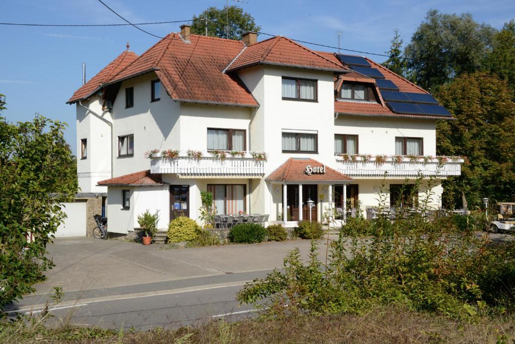 a large white house with a red roof at Hotel Bliesbrück in Herbitzheim