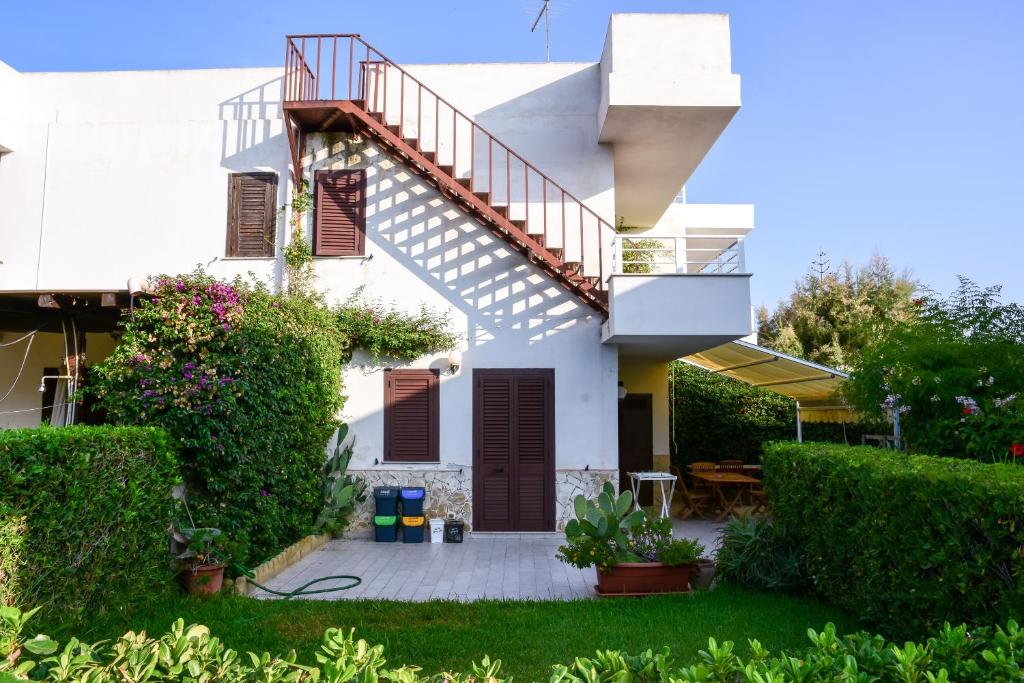 a white house with a staircase and plants at solemaremarzamemi in Marzamemi