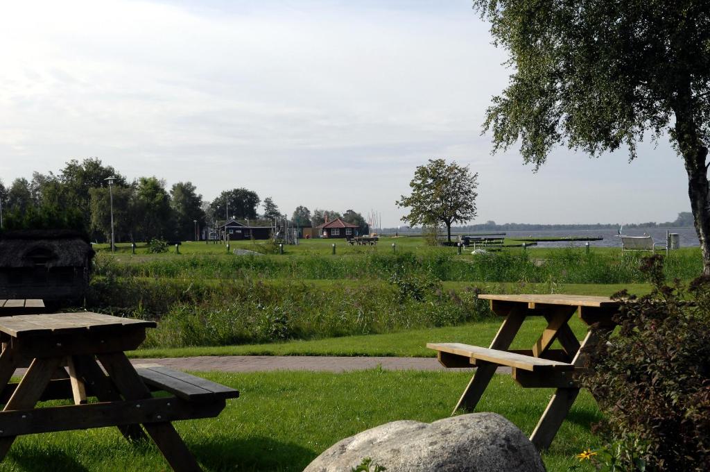 two picnic tables in a park with a field at Reiherweg3A in Südbrookmerland