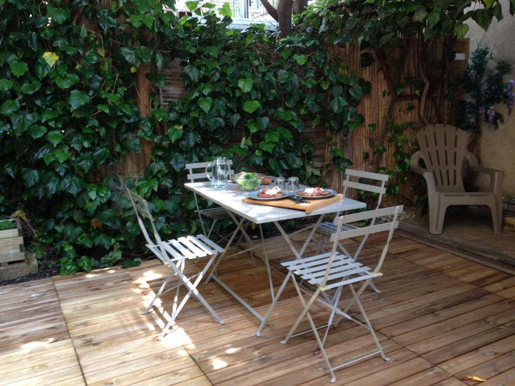 una mesa y sillas en un patio con un seto en 6A en Aviñón