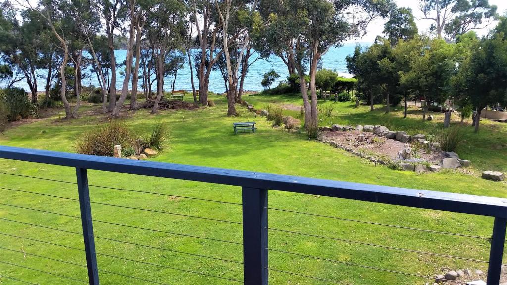 einen Balkon mit Blick auf einen Park mit einer Bank in der Unterkunft Four Seasons Waterfront Villas in Taranna