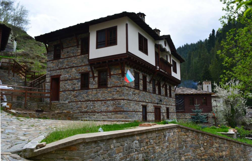 a large stone building with a white window on it at Къща за гости Гайтана in Shiroka Laka