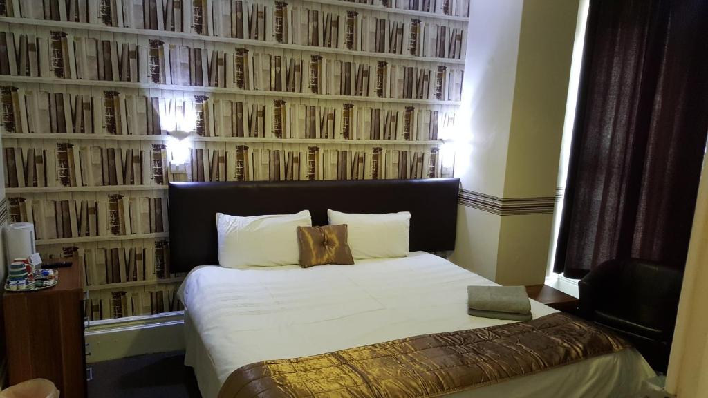 a bedroom with a bed with a wall of books at Portsmouth Budget Hotels - All rooms are EN-SUITE in Portsmouth
