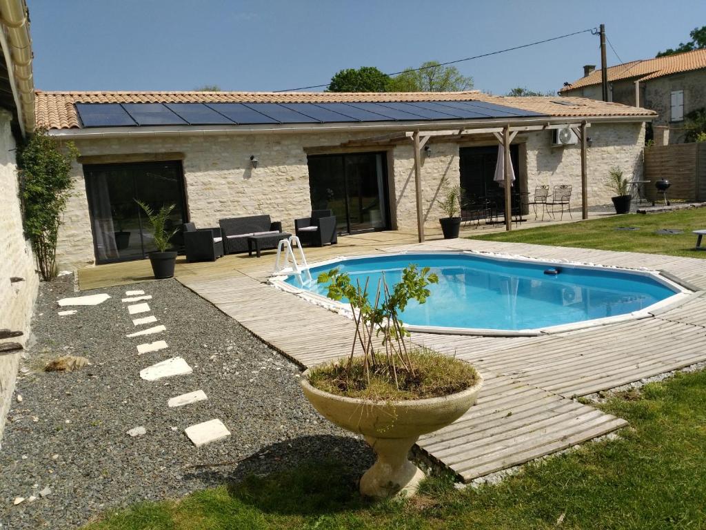 una piscina en un patio con terraza de madera en Gite Sud Deux Sevres en Marigny