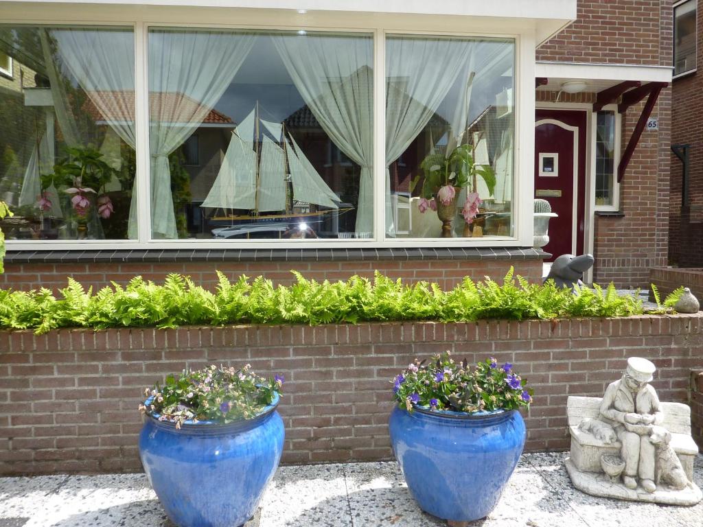 dos jarrones azules con flores delante de una ventana en Studio Zandvoort, en Zandvoort