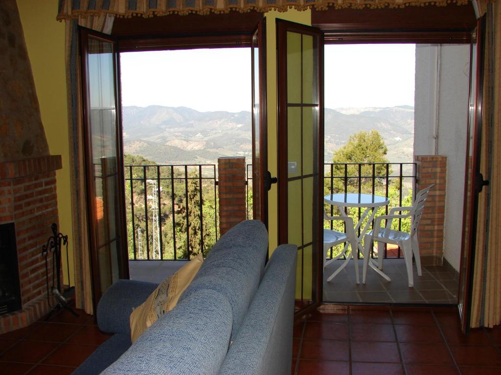 Una sala de estar con un sofá y una mesa en un balcón. en Apartamentos Sierra de Segura, en Segura de la Sierra