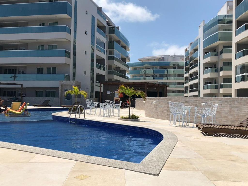 una piscina con mesas, sillas y edificios en Le Bon Vivant 307 B, en Arraial do Cabo